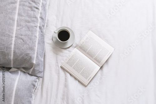 Open book  and cup of coffee in bed 