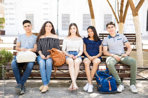 Smiling teenagers sitting outdoors on a bench