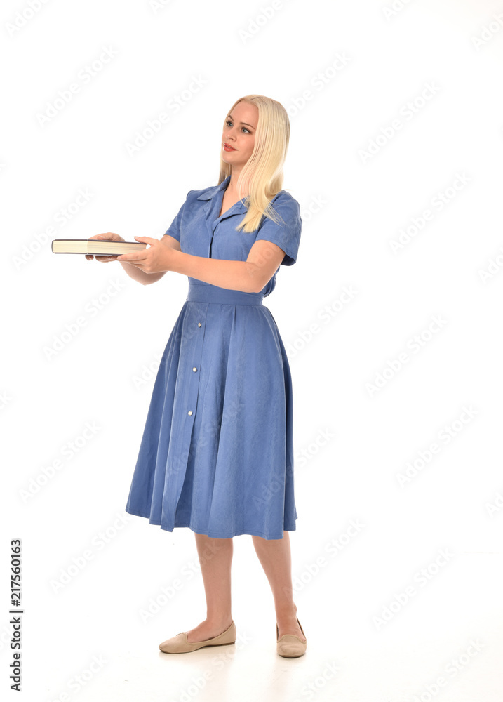 full length portrait of blonde girl wearing blue dress. standing pose holding a book. isolated on white studio background. full length portrait of blonde girl wearing blue dress. standing pose holding a book. isolated on white studio background.