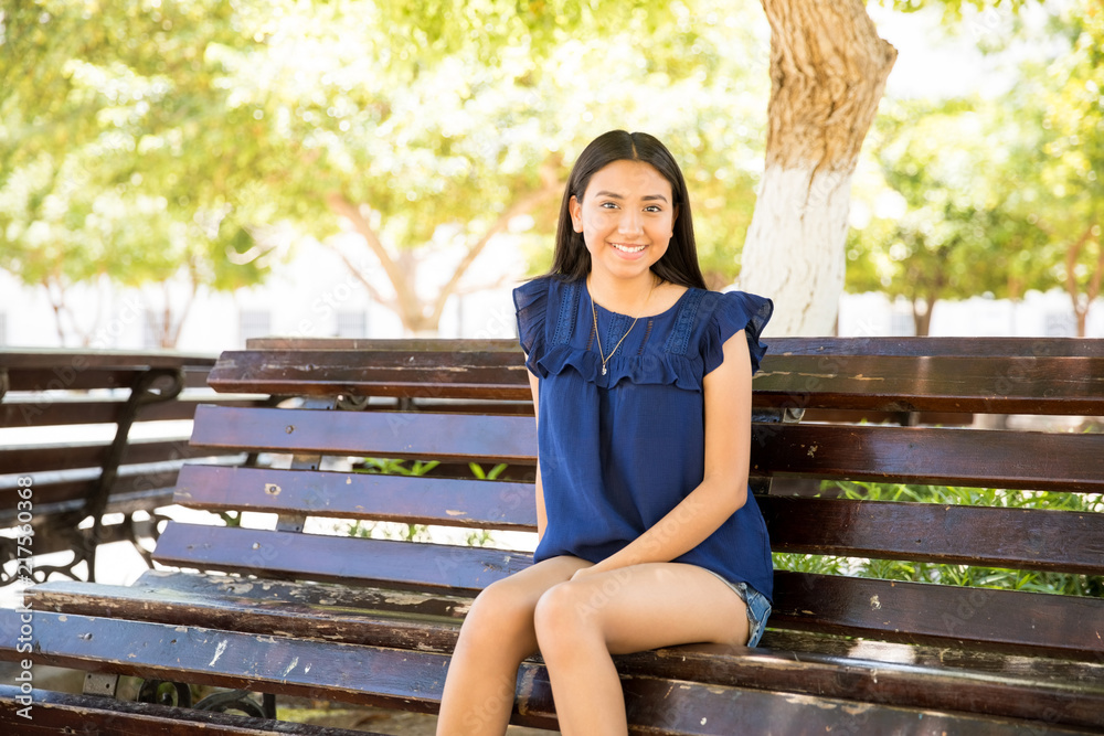 Good looking teenage girl relaxing on bench outdoors Good looking teenage girl relaxing on bench outdoors