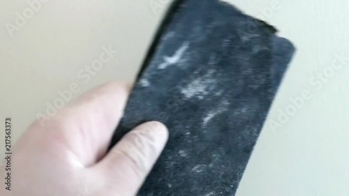 a painter fixes the house wall with sandpaper,

