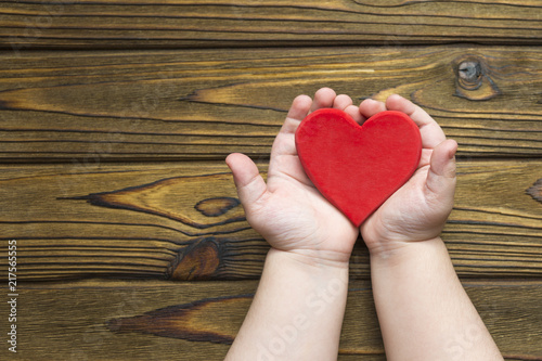 the child's hands hold a red heart