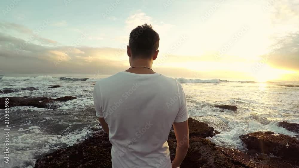 Adult guy walking slowly by the ocean, stabilized camera following him. Bali Indonesia. Adult guy walking slowly by the ocean, stabilized camera following him. Bali Indonesia.