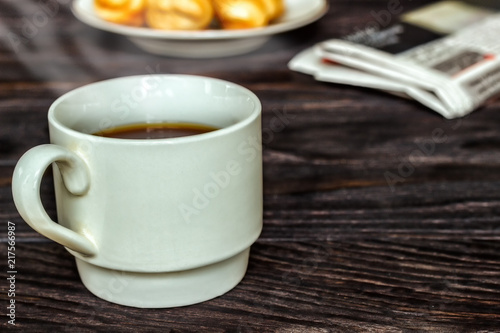 White cup with coffee and croissants on a wooden background  selective focus. The concept of breakfast.