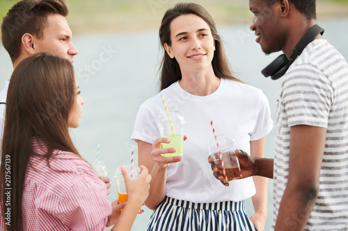Group of friends standing and drinking cocktails at a party outdoors