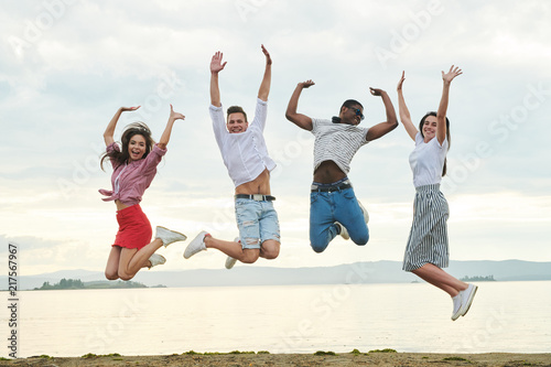 Happy young people jumping together on the beach © Seventyfour