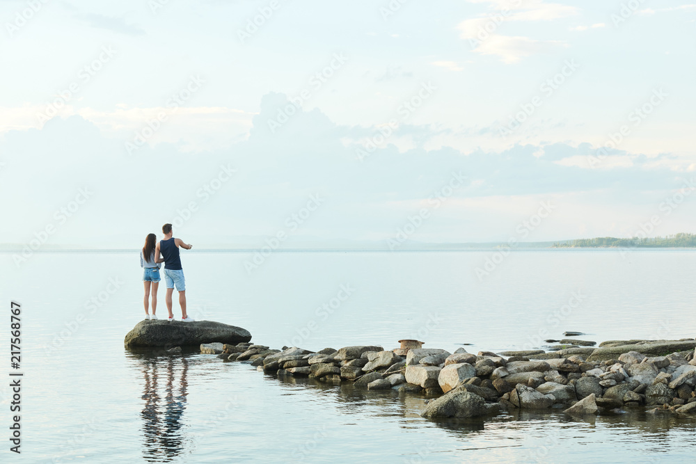 Rear view of young couple standing on stones and enjoying beautiful view