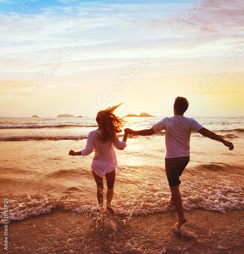 happy couple on honeymoon vacation travel, romantic dream beach holidays, happiness background, silhouettes of man and woman running to the sea at sunset together