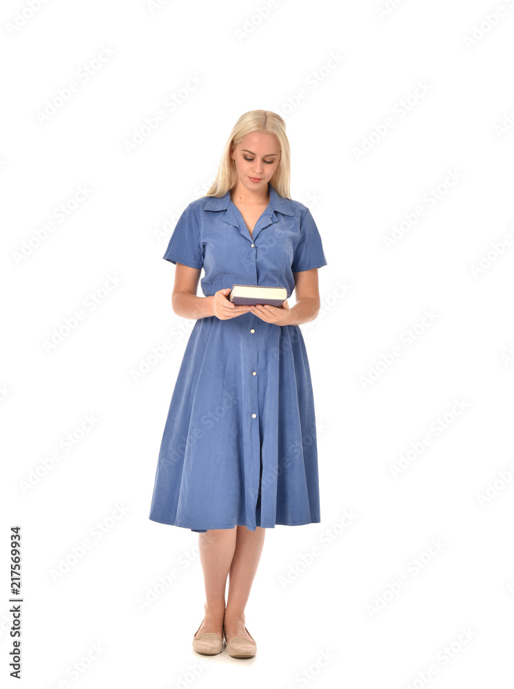 full length portrait of blonde girl wearing blue dress. standing pose holding a book. isolated on white studio background. full length portrait of blonde girl wearing blue dress. standing pose holding a book. isolated on white studio background.