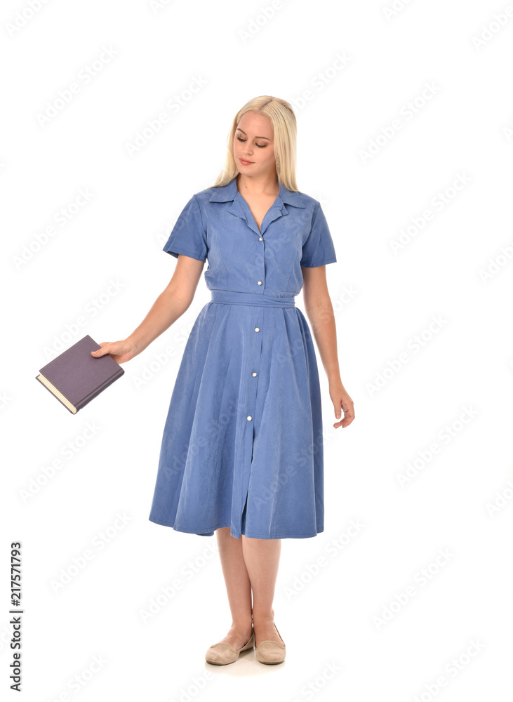 full length portrait of blonde girl wearing blue dress. standing pose holding a book. isolated on white  studio background.