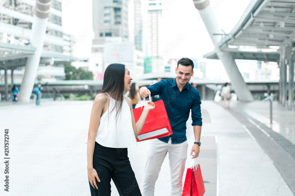 Happy couple with shopping bags at outdoors. Wife makes her husband surprised with the purchase. concept of business shopping, buyer, consumer and attractive lover.