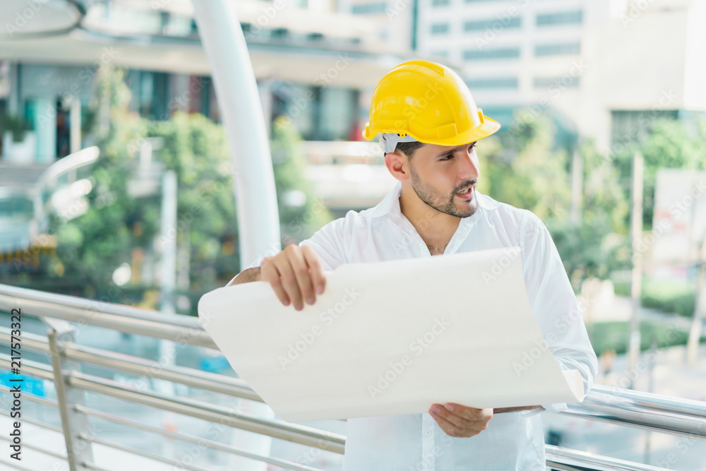 Engineer man wearing safety helmet and hold blueprint document at construction site. concept of work office, security consult, job control, development and business process. Engineer man wearing safety helmet and hold blueprint document at construction site. concept of work office, security consult, job control, development and business process.