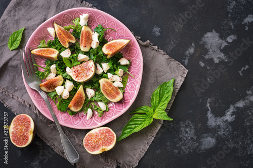 Dietary salad figs, goat cheese, green leaves, dark rustic concrete ofn. Flat lay of the copy space. Mediterranean food. photo