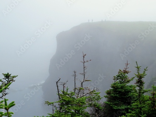 Misty cliffs with hikers on the edge, Skerwink Trail, Newfoundland and Labrador, Canada photo
