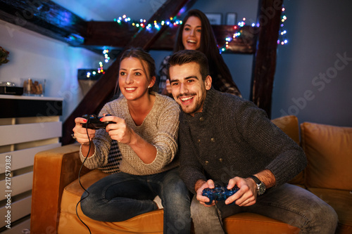 Foto Group of best friends sitting at home on pleasant evening and playing games on console