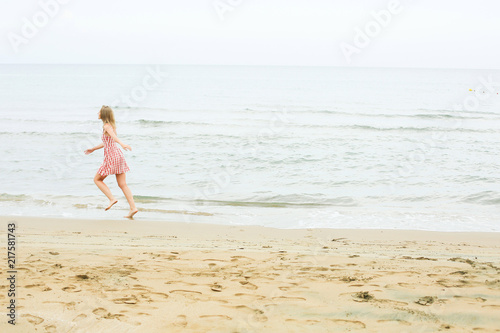 woman is running along seashore  wearing short red dress