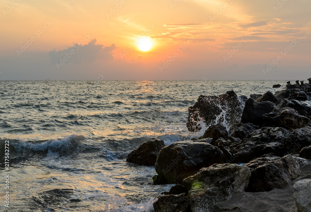 Waves splashing rocks at sunrise