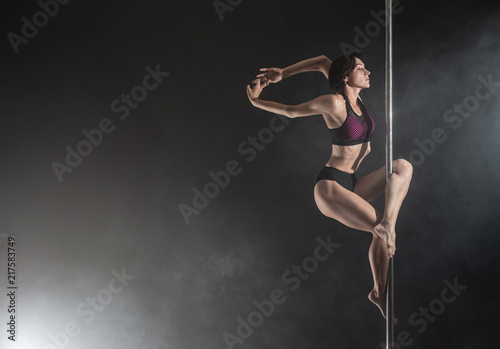 Beautiful slim girl with pylon. Female pole dancer dancing on a black background © Vladimir