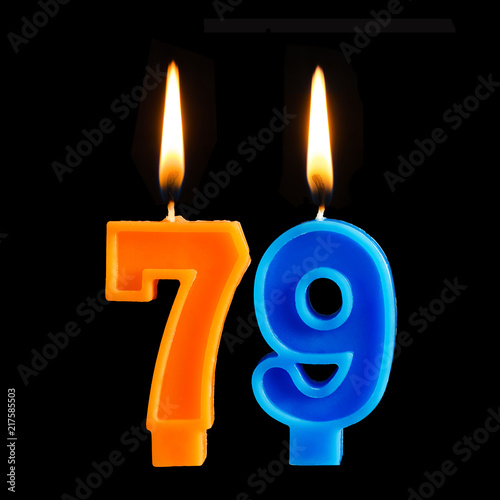 Birthday burning candles in the form of 79 seventy nine for cake isolated on black background.