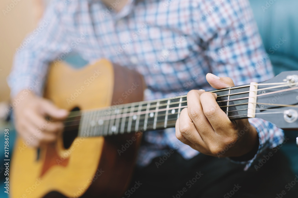 Stylish hipster guy Acoustic Guitar Playing by hand. Artist young male musician Plaid shirt Playing Acoustic Guitar in sofa living room parlor.	