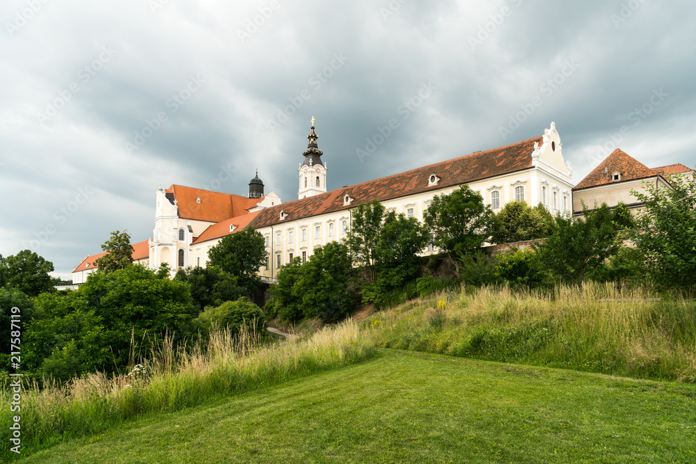 Stift Altenburg vor wolkenverhangenem Himmel mit Wiese im Vordergrund und Weg zum Stift