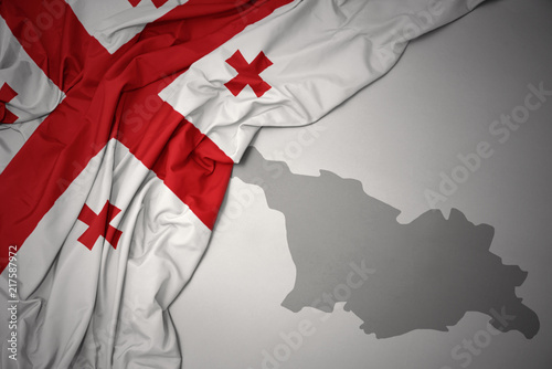 Foto waving colorful national flag and map of georgia.