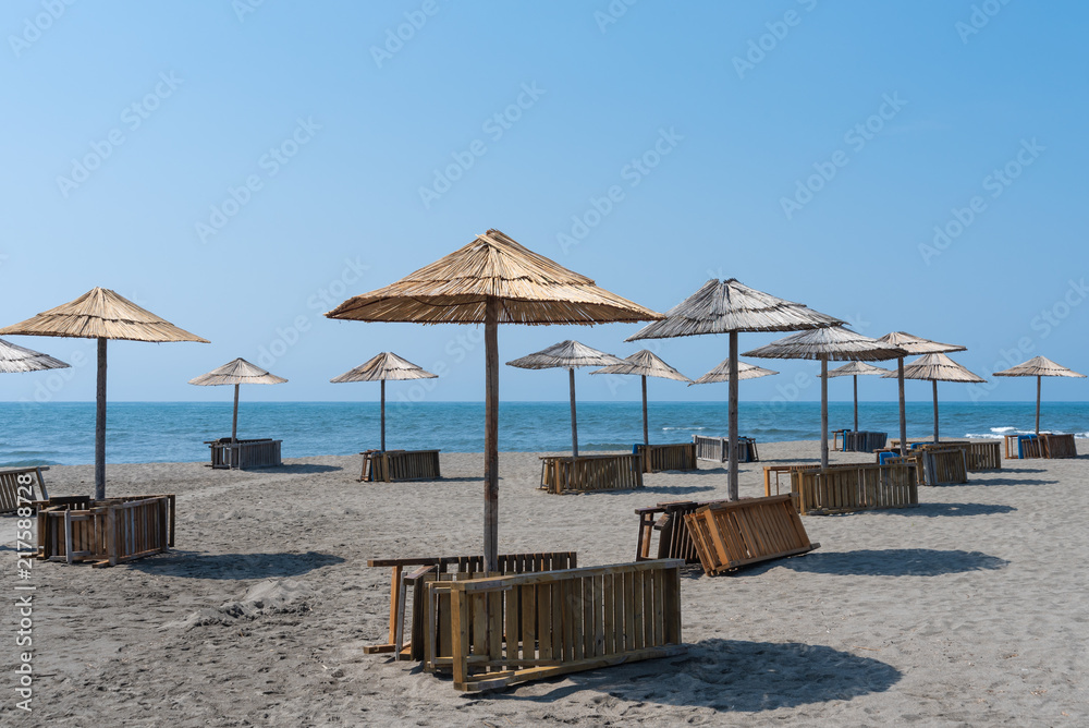 Panorama with sandy beach with wooden umbrellas and deck chairs