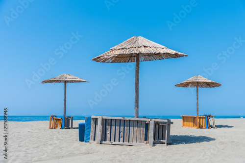 Fototapeta Naklejka Na Ścianę i Meble -  Panorama with sandy beach with wooden umbrellas and deck chairs