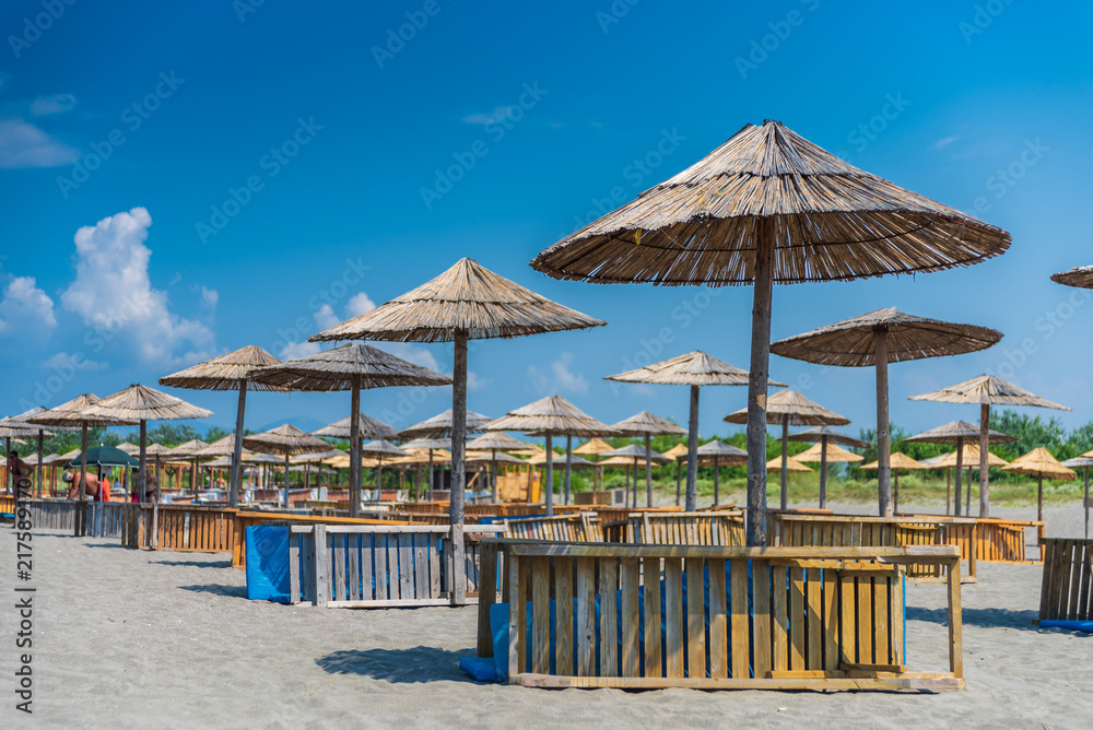 Fototapeta premium Panorama with sandy beach with wooden umbrellas and deck chairs