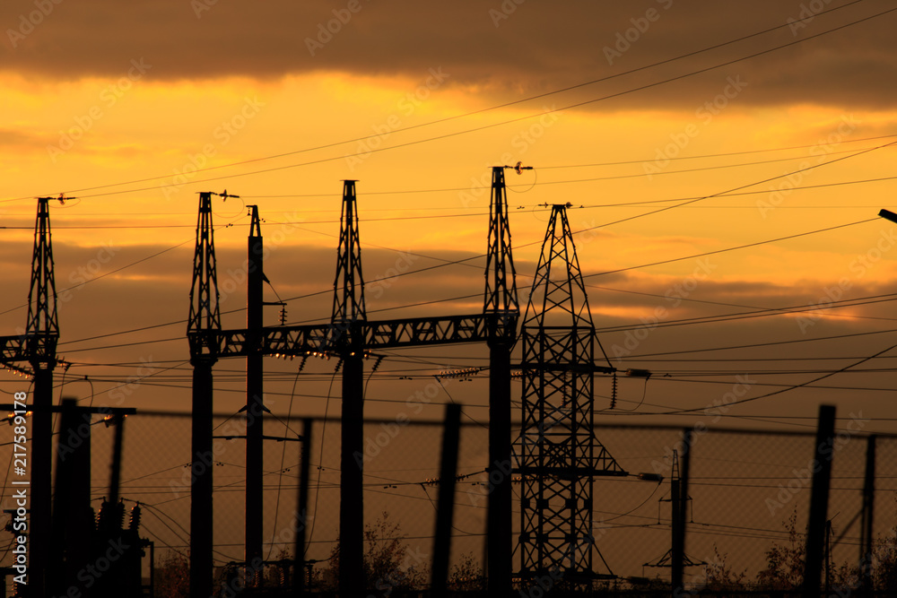 poles at a power plant at sunset as a background