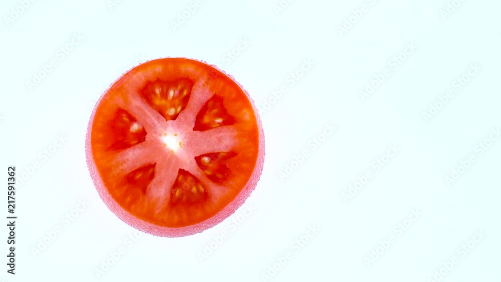 Half frame of a top view from above of a cross section of red tomato. Rotating on the turntable isolated on the white background. Close-up. Macro. Half frame of a top view from above of a cross section of red tomato. Rotating on the turntable isolated on the white background. Close-up. Macro.