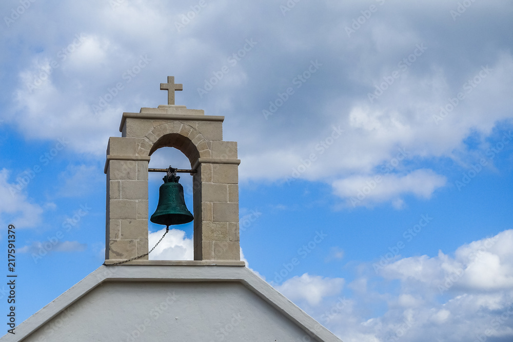 In the close-up is a church tower with a green call, with blue skies and white clouds in the background.