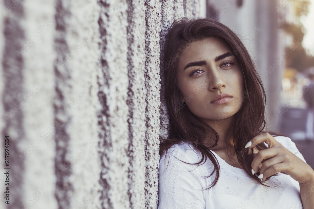 Fototapeta premium Fashion portrait of a beautiful young woman. Sexual brunette female outside looks into the camera. 