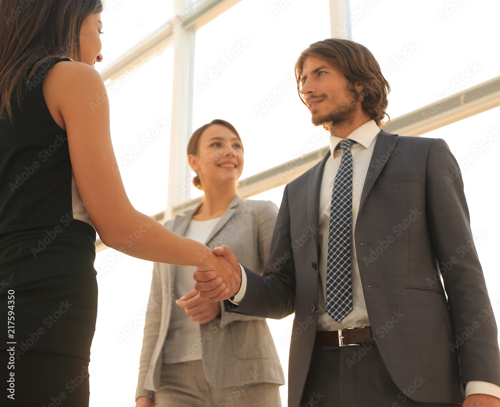 Businesspeople shaking hands against room with large window loo Businesspeople shaking hands against room with large window loo