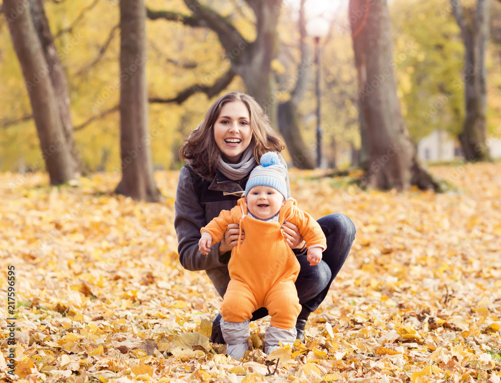 Mother playing in park with her toddler baby. Mom and son over seasonal autumn background. Mother playing in park with her toddler baby. Mom and son over seasonal autumn background.