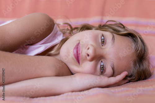 portrait of a young beautiful kid resting on bed and smiling. Family lifestyle indoors. Relax concept