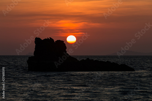 Sunrise over a tropical ocean with a large rock in silhouette (Myanmar) photo