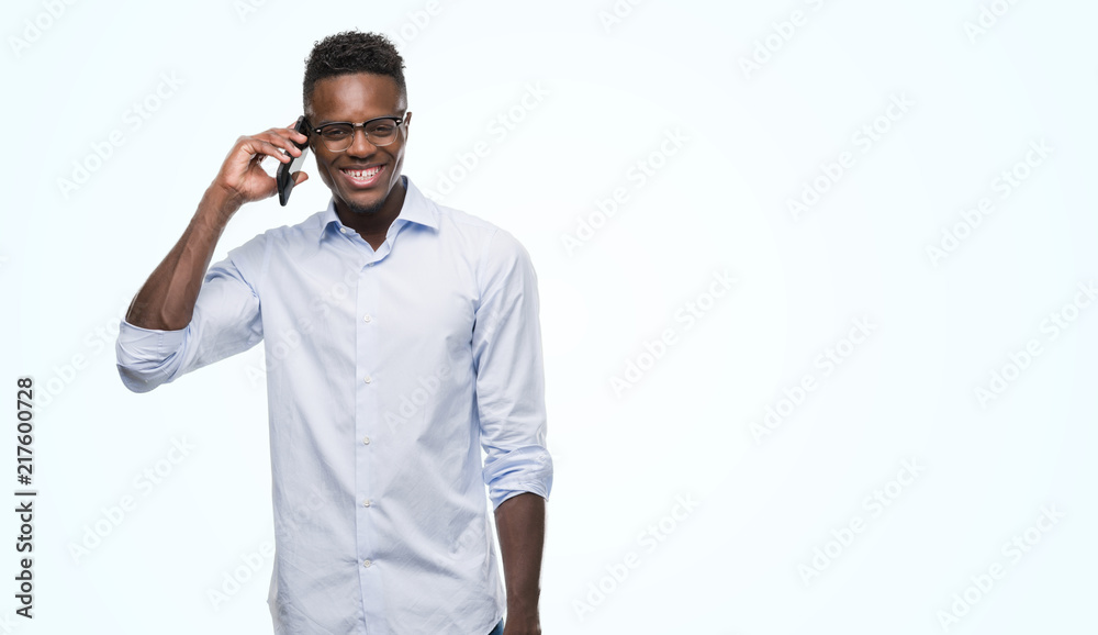 Young african american man using smartphone with a happy face standing and smiling with a confident smile showing teeth Young african american man using smartphone with a happy face standing and smiling with a confident smile showing teeth