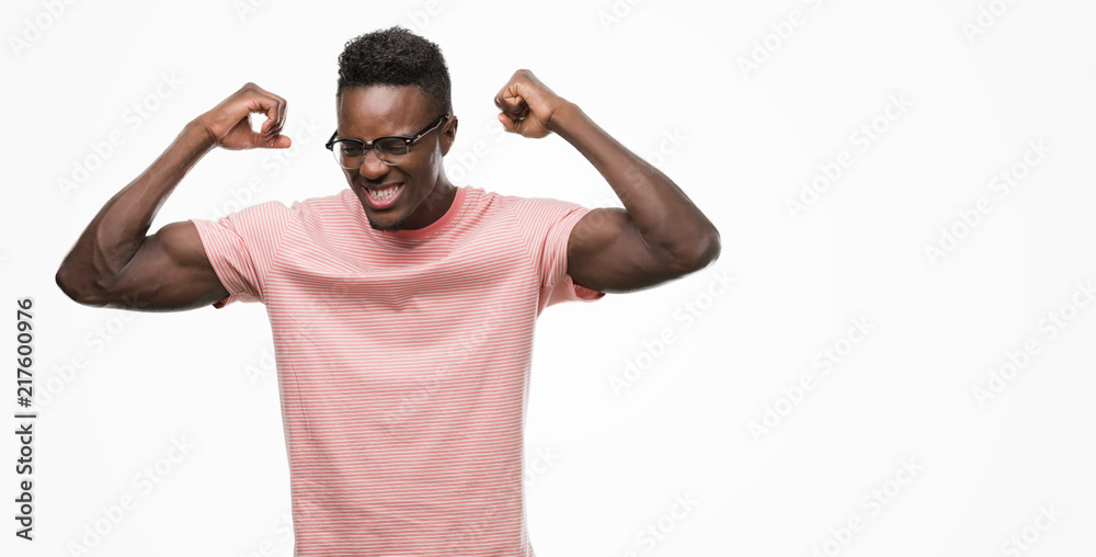 Young african american man wearing pink t-shirt showing arms muscles smiling proud. Fitness concept. Young african american man wearing pink t-shirt showing arms muscles smiling proud. Fitness concept.