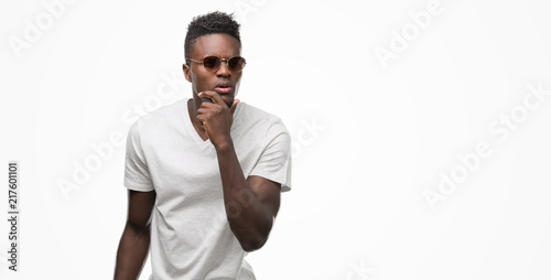 Young african american man wearing sunglasses serious face thinking about question, very confused idea