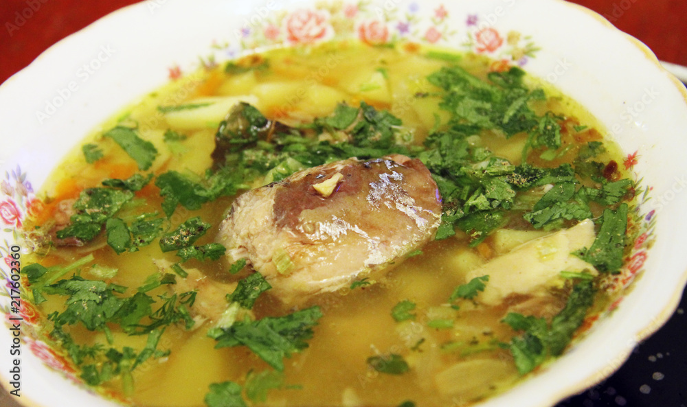 Fish soup in the white bowl with herbs and spoon