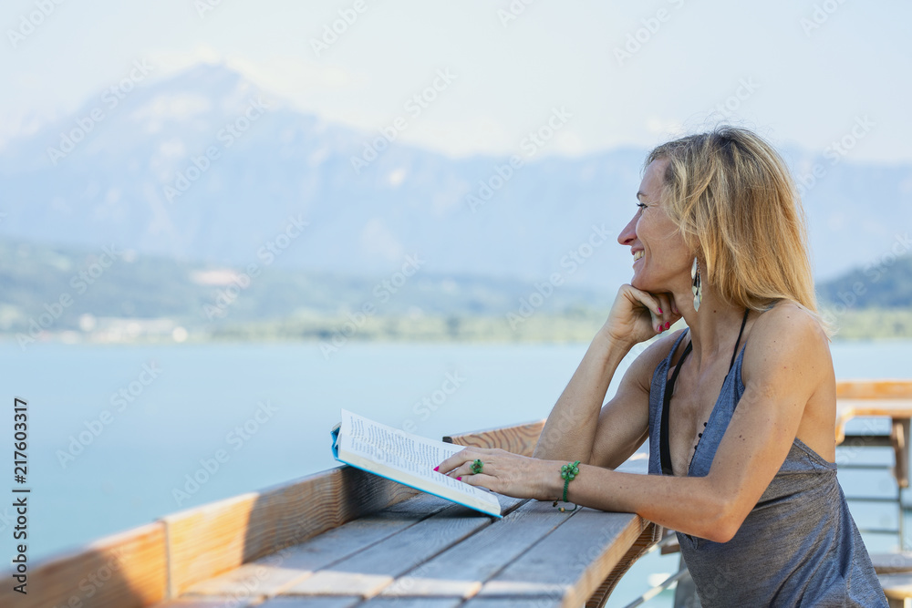 Girl reading a book by the lake.