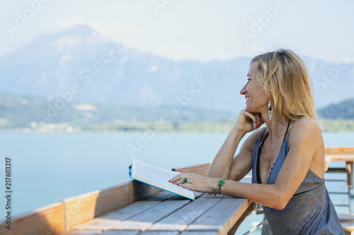 Girl reading a book by the lake.