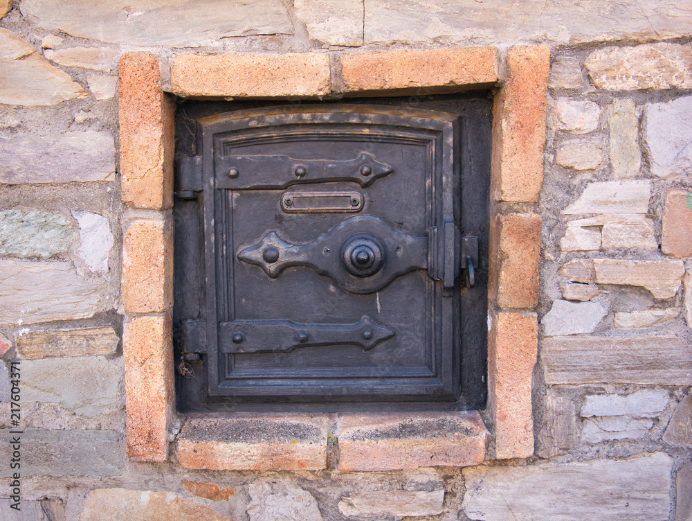 Tür von einem alten Backofen außen an der Fassade