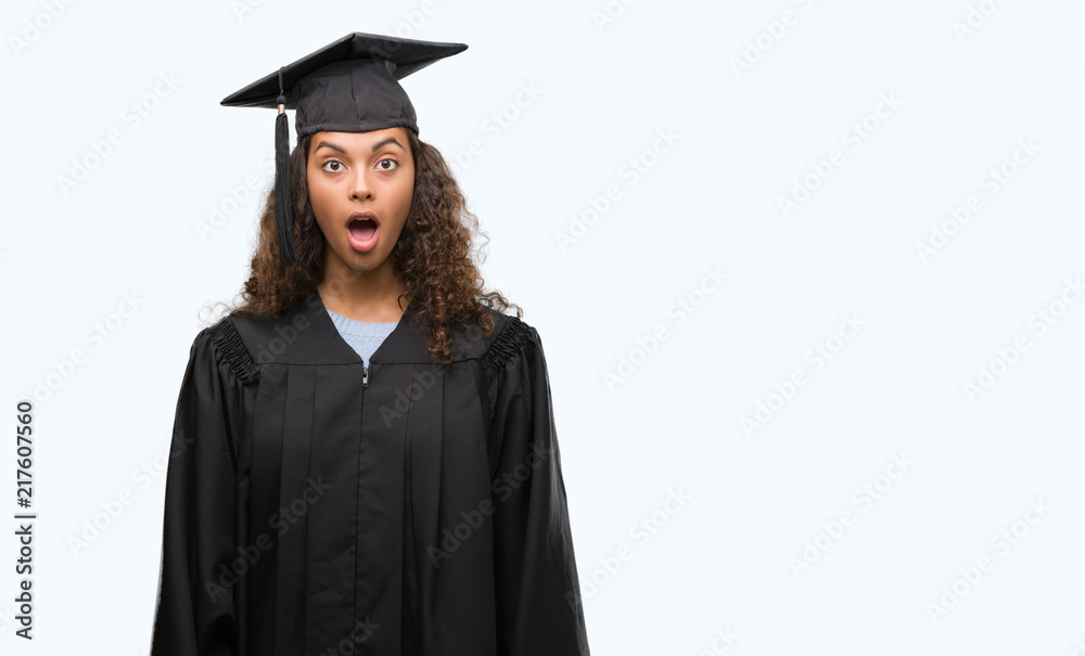 Young hispanic woman wearing graduation uniform scared in shock with a surprise face, afraid and excited with fear expression Young hispanic woman wearing graduation uniform scared in shock with a surprise face, afraid and excited with fear expression