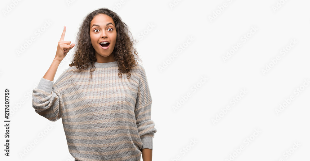 Beautiful young hispanic woman wearing stripes sweater pointing finger up with successful idea. Exited and happy. Number one. Beautiful young hispanic woman wearing stripes sweater pointing finger up with successful idea. Exited and happy. Number one.