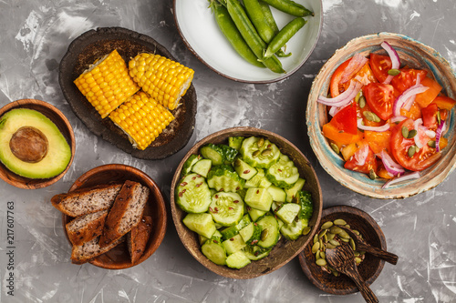 Clean eating concept. Cucumber salad, tomato salad, flax bread, avocado, corn. Top view, food background.