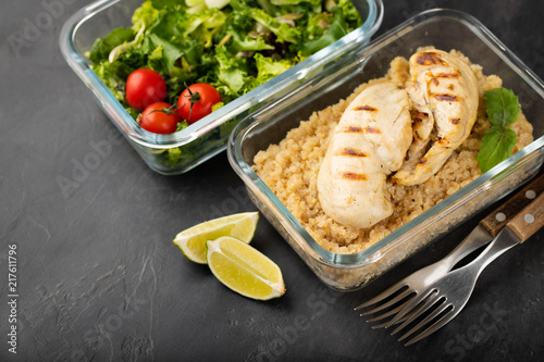 Healthy meal prep containers with quinoa, chicken breast and green salad overhead shot with copy space