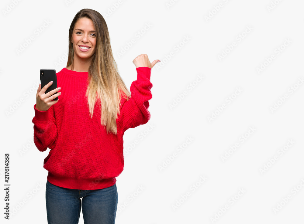 Beautiful young woman using smartphone pointing with hand and finger up with happy face smiling Beautiful young woman using smartphone pointing with hand and finger up with happy face smiling