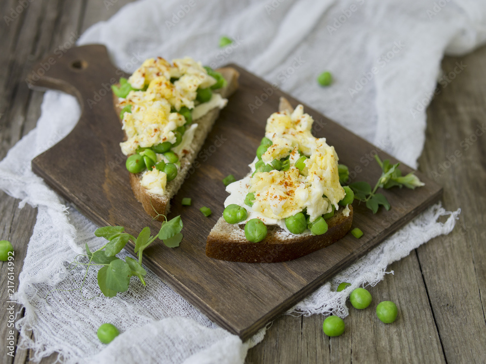 Bruschetta with green peas, cheese and egg on a wooden board. Close up, copy space Bruschetta with green peas, cheese and egg on a wooden board. Close up, copy space